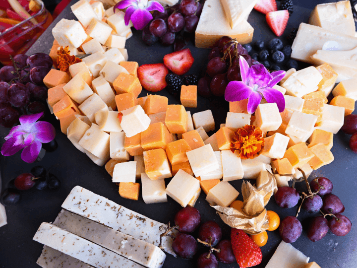 cheese board with grapes, berries and edible flowers.