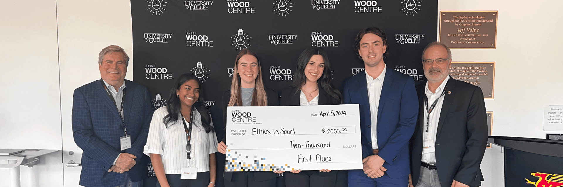 4 students standing with 2 professors and large cheque
