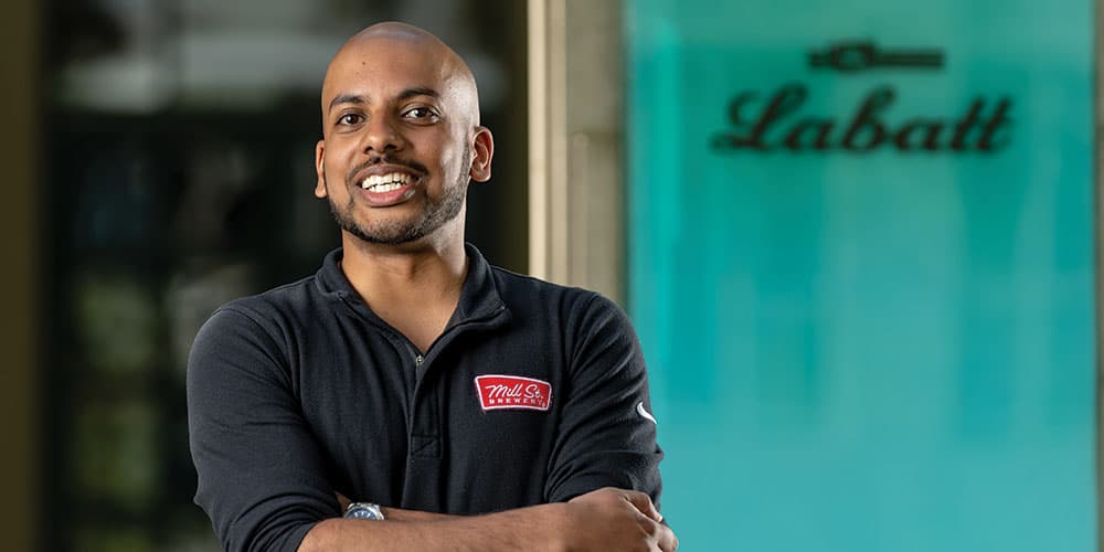 Lang business school alumni Ryan Padum in a power pose smiling with the Labatt logo in the background.