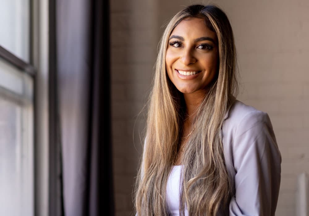Lang business school alumni Tara Lalani standing by a window smiling.