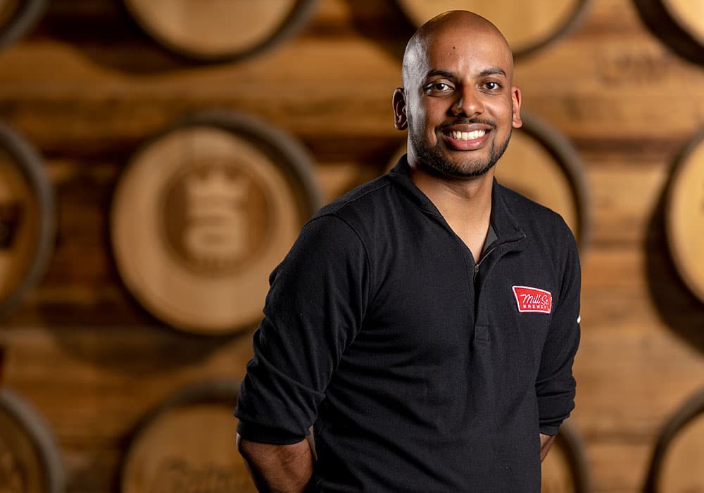 Lang business school alumni Ryan Padum standing smiling with Labatt barrels in the background.