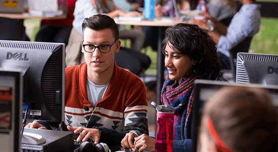 Two students sitting at a computer in the library