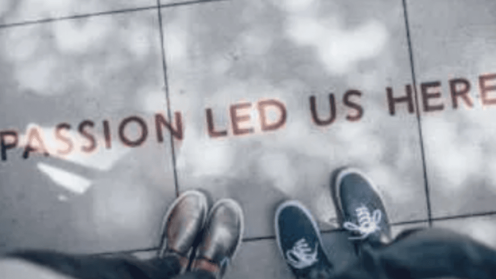 Two pairs of shoes with passion led us here written on the cement.