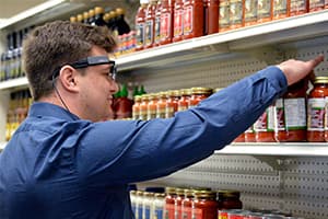 a photo of a student wearing smart glasses picking out a jar of sauce