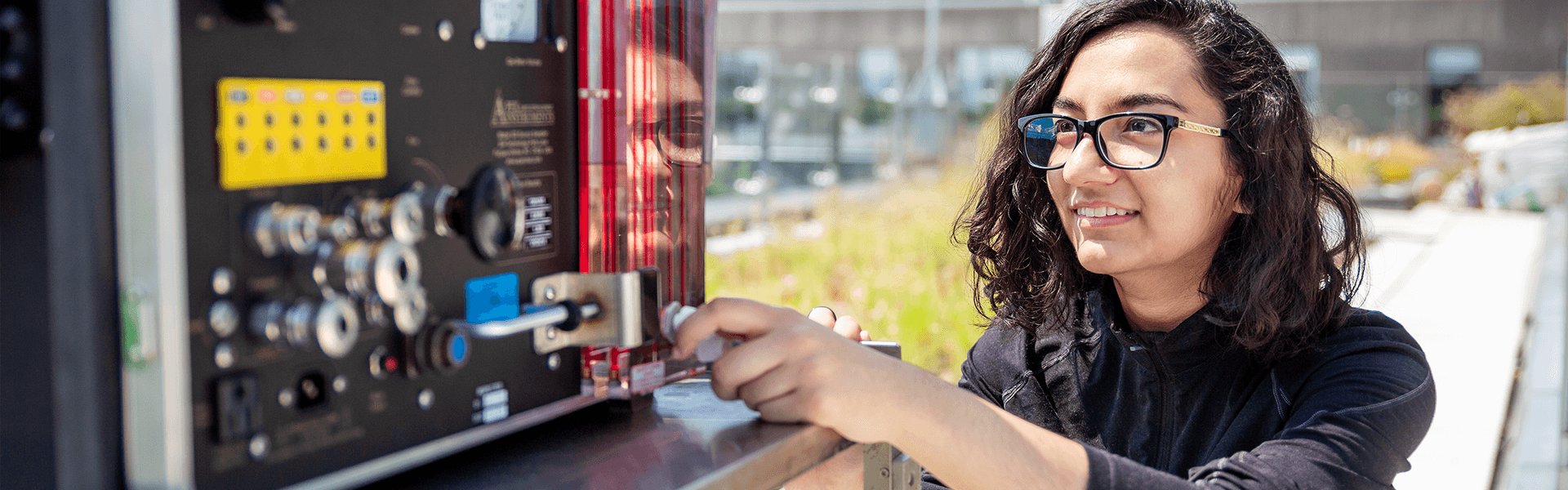 Female student adjusting a knob on a wind-reading device