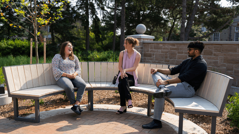 Three Lang students sitting on a bench in Lang Plaza