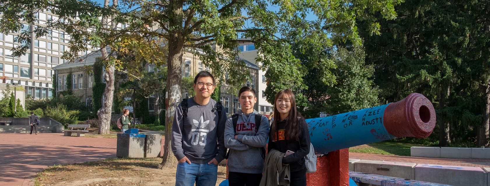 Three international students in front of the cannon.