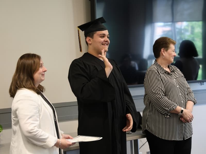 A graduating student receiving an award waves to his family in the crowd.