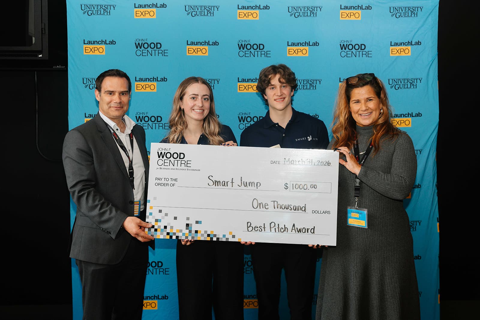 4 individuals holding a cheque with the text " Best Pitch - SmartJump"