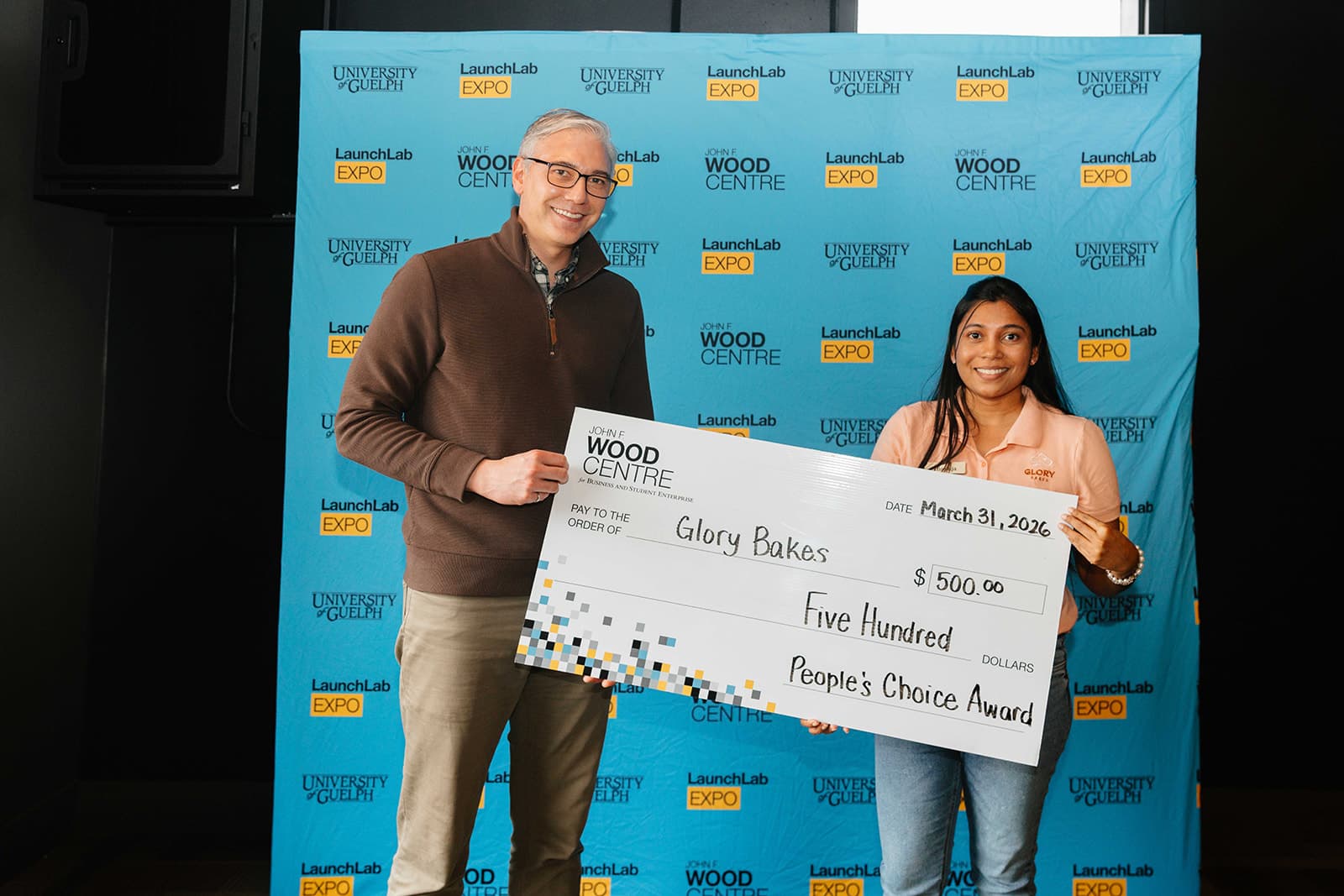 2 people holding a cheque with the text 'Glory Bakes - People's Choice