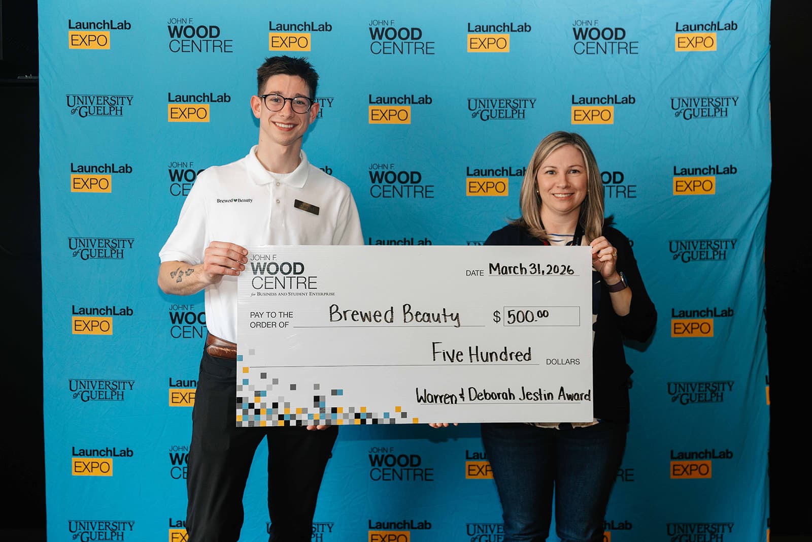 2 individuals holding a cheque with the text 'brewed beauty"